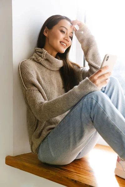 Imagem Sorrindo Mulher Asiática Digitando Telefone Celular Enquanto Sentado Soleira — Fotografia de Stock