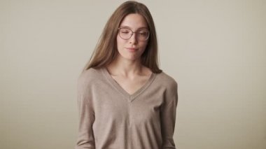 Gri duvar arkasında izole edilmiş güzel, güvenilmez, genç ve güzel bir kadın.