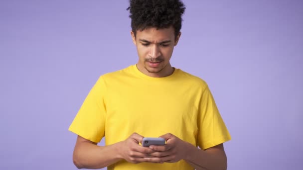 Joven Africano Sorprendido Chico Aislado Sobre Púrpura Fondo Usando Teléfono — Vídeo de stock