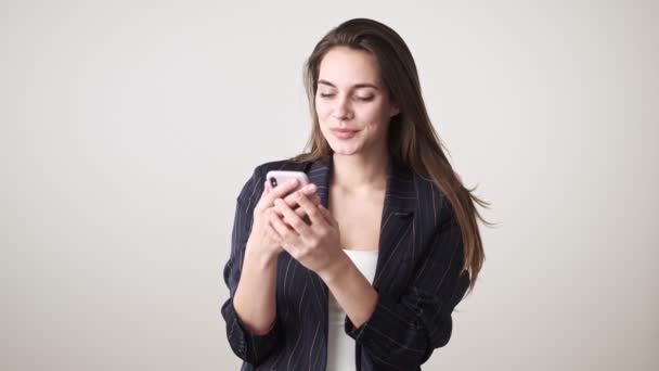 Piękna Młoda Kobieta Luźnych Ubraniach Używa Swojego Smartfona Stojącego Białym — Wideo stockowe