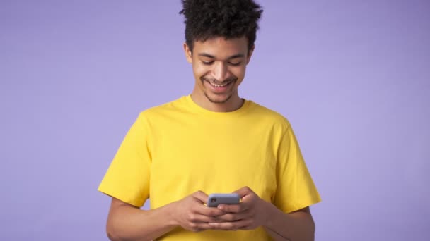 若いアフリカの正の幸せな男隔離以上紫背景使用して携帯電話 — ストック動画