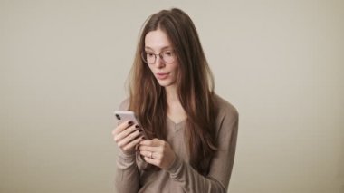 Gri duvar arkaplanından izole edilmiş genç, mutlu, güzel bir kadın.