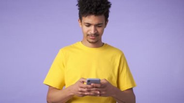 Genç Afrikalı duygusal şokta olan adam mor arka planda cep telefonuyla izole edilmiş.