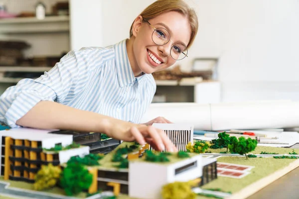 Фотографія Радісної Молодої Жінки Архітектора Окулярах Розробляє Проект Моделлю Будинку — стокове фото