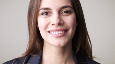 Gülümseyen bir kadının yakın plan görüntüsü, stüdyoda beyaz arka planda izole bir şekilde dururken bir şeye katılıyor.