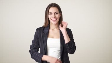 Gündelik kıyafetler giyen çekici bir genç kadın gülümsüyor. Kollarını katlayarak stüdyoda beyaz arka planda soyutlanmış bir şekilde duruyor.