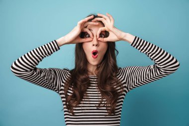 Mavi arka planda parmaklarıyla eğlenen eğlenceli genç bir kadın görüntüsü