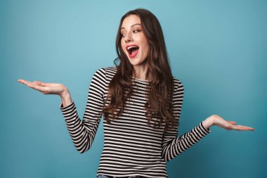 Mavi arka planda gülümseyen ve kopyalama alanını tutan neşeli beyaz kadın görüntüsü