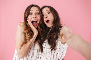 Pembe arka planda izole edilmiş selfie çekerken şaşıran güzel kadınların görüntüsü