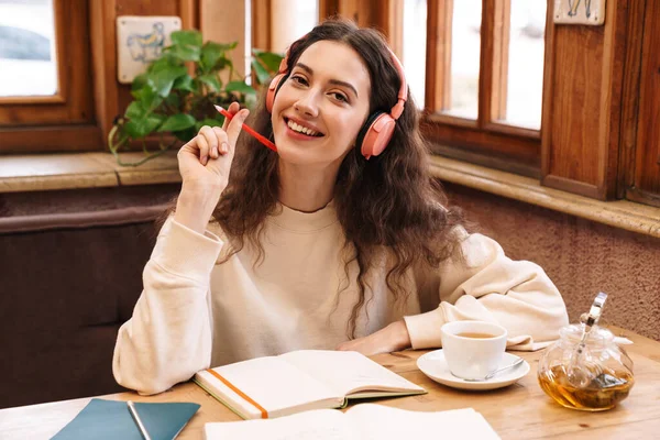 Εικόνα Χαρούμενης Μαθήτριας Που Χρησιμοποιεί Ασύρματα Ακουστικά Ενώ Κάνει Την — Φωτογραφία Αρχείου