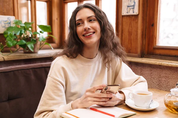 Bild Einer Fröhlichen Studentin Die Hausaufgaben Macht Und Ihr Handy — Stockfoto