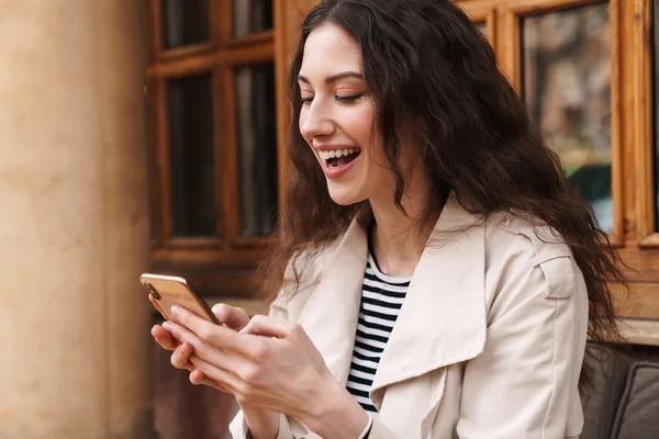 Зображення Щасливої Брюнетки Використовуючи Мобільний Телефон Посміхаючись Сидячи Вуличному Кафе — стокове фото