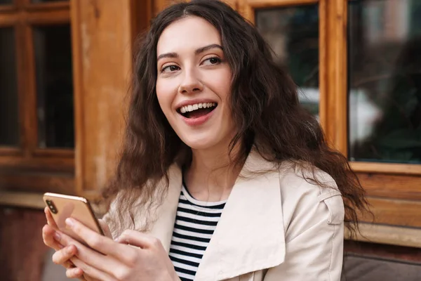 Изображение Счастливой Брюнетки Использующей Мобильный Телефон Улыбающейся Сидя Уличном Кафе — стоковое фото