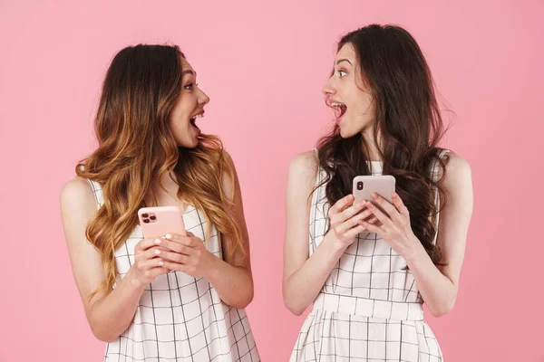 ピンクの背景に隔離された携帯電話を使い 驚きを表現する興奮した白人女性のイメージ — ストック写真
