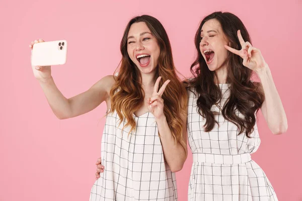 분홍색 배경으로 Selfie 전화로 분리하면서 표시를 여성들의 — 스톡 사진