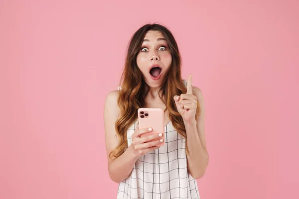Kép Megdöbbent Aranyos Segítségével Mobiltelefon Mutató Ujját Felfelé Elszigetelt Rózsaszín — Stock Fotó