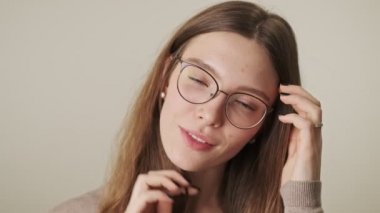 Gri duvar arkasında izole edilmiş gülümseyen genç kadın.