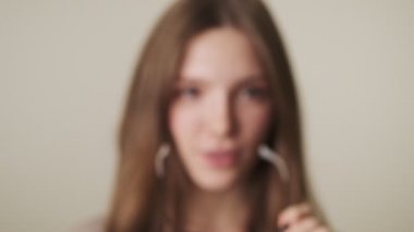 Gri duvar arka planında gözlüklü, mutlu genç bir kadın.