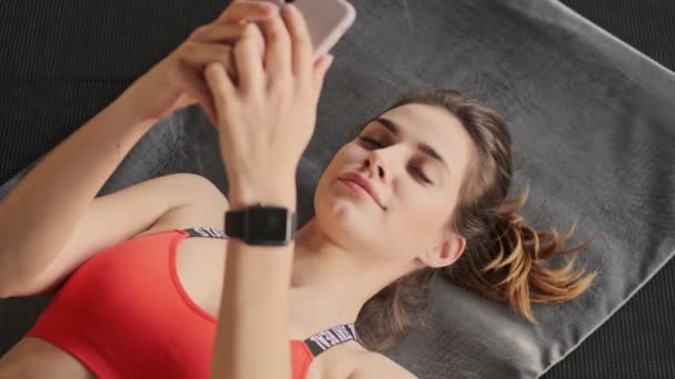 Νεαρή Όμορφη Συμπυκνωμένη Γυναίκα Γυμναστικής Χρησιμοποιώντας Κινητό Τηλέφωνο — Αρχείο Βίντεο