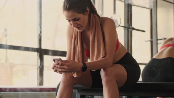 年轻的健身女子在健身房里喜欢用手机看钟表 — 图库视频影像