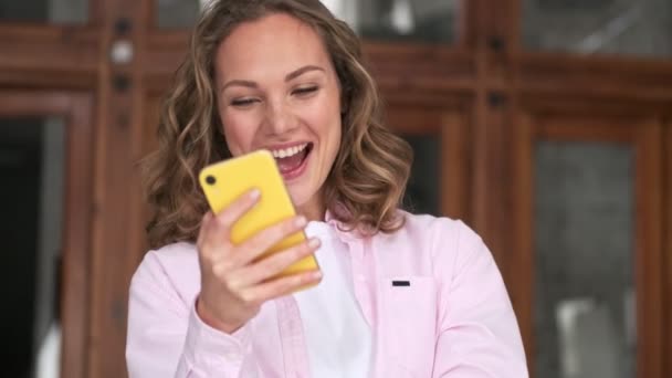 Seorang Wanita Muda Pirang Yang Bahagia Adalah Menonton Sesuatu Smartphone — Stok Video