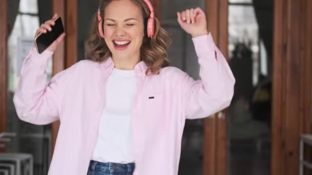Счастливая Веселая Молодая Женщина Удовольствием Слушает Музыку Розовых Беспроводных Наушниках — стоковое видео