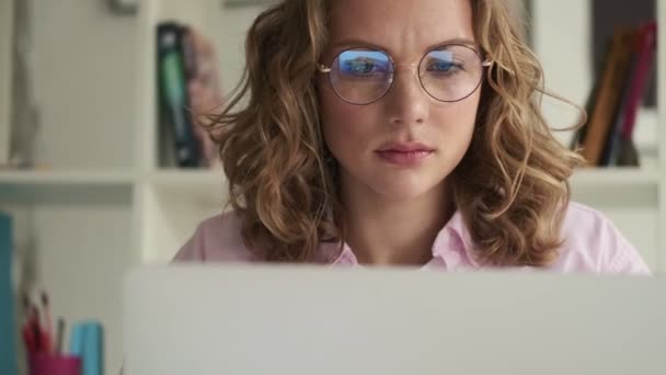 Düşünceli Hoşnutsuz Ciddi Gözlüklü Genç Bir Sarışın Laptopunu Kullanarak Çalışıyor — Stok video