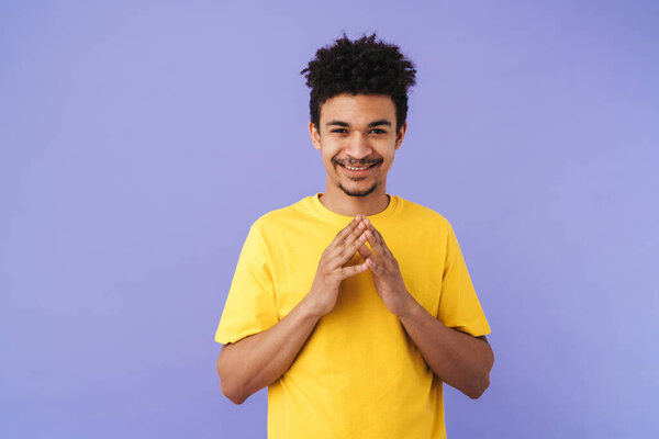 Фото приятного африканского американца, улыбающегося и смотрящего на камеру на фиолетовом фоне
