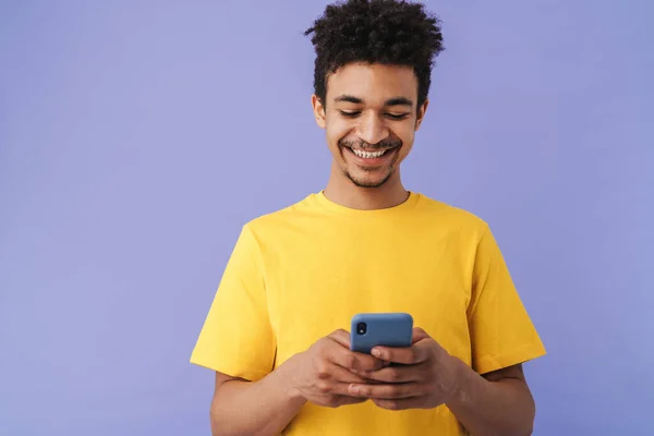 照片上的兴奋的非洲裔美国人笑着用智能手机隔离紫色背景 — 图库照片