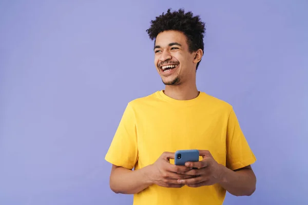 照片中滑稽的非洲裔美国人笑着用紫色背景的智能手机 — 图库照片