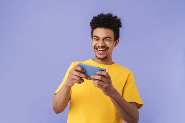 非洲裔美国人在紫色背景的智能手机上玩电子游戏的照片 — 图库照片