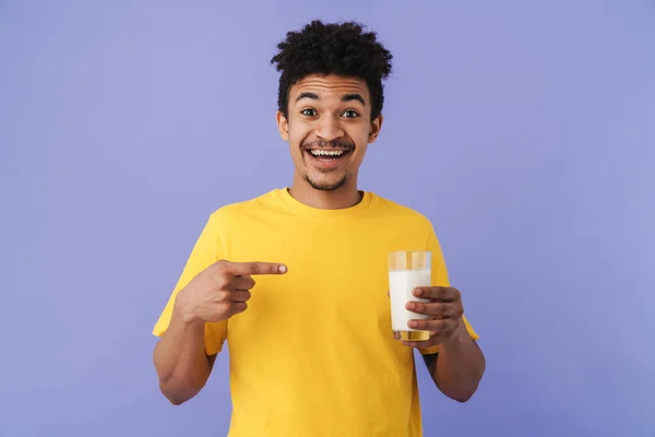 照片上的兴奋的非洲裔美国人用手指着杯子 牛奶隔着紫色的背景 — 图库照片