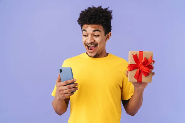 Foto Homem Afro Americano Espantado Segurando Caixa Presente Celular Isolado — Fotografia de Stock