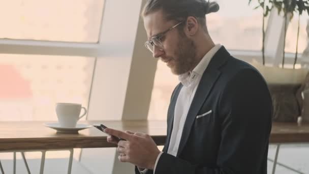 Sidovy Stilig Ung Skäggig Affärsman Använder Sin Smartphone Medan Dricker — Stockvideo