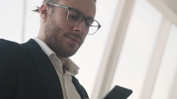 Ein Gutaussehender Junger Geschäftsmann Benutzt Sein Smartphone Während Drinnen Einem — Stockvideo
