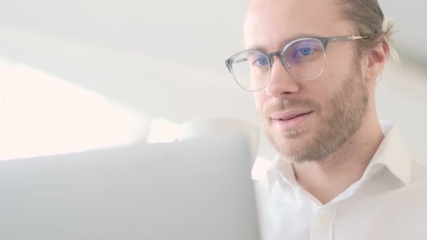 一个成功的戴眼镜的年轻生意人的近照是 他在市区一家咖啡馆里喝咖啡时使用笔记本电脑 — 图库视频影像