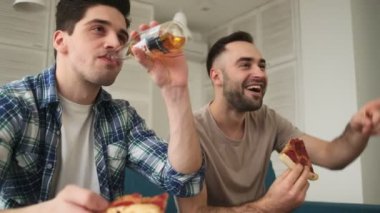Neşeli, güler yüzlü bir adam evde oturmuş abur cubur, pizza yiyip bira içerken televizyon seyrediyor.