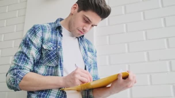 Ein Fokussierter Mann Macht Sich Notizen Während Hause Eine Papiermappe — Stockvideo