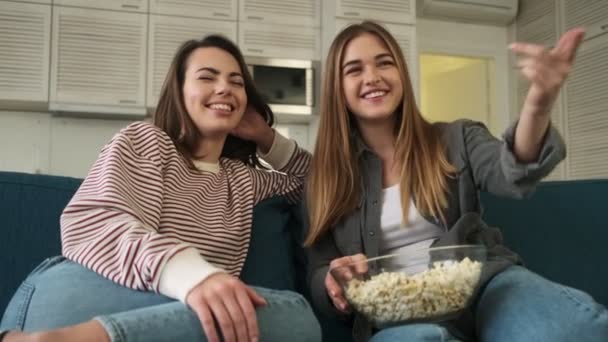 Śmiejące Się Szczęśliwe Dziewczyny Oglądają Coś Śmiesznego Jedząc Popcorn Salonie — Wideo stockowe