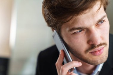 Kafkasyalı, bıyıklı vahşi iş adamının kapalı alanda cep telefonuyla konuştuğu fotoğraf.