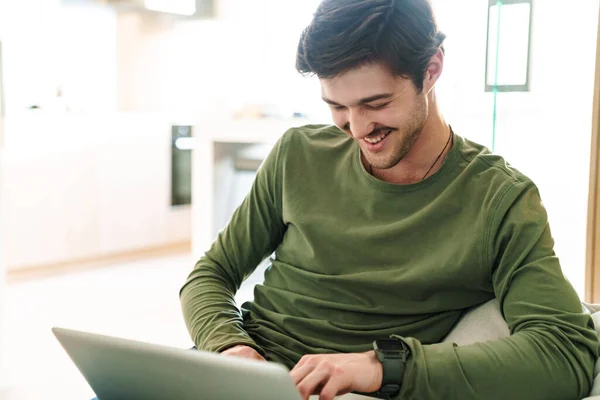 Foto Skrattande Ung Man Med Mustasch Skriva Laptop Medan Sitter — Stockfoto