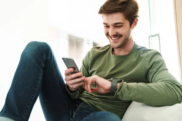 Foto Van Vrolijke Jongeman Met Snor Lachend Smartphone Zittend Bank — Stockfoto