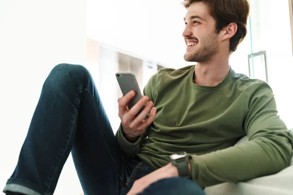 Foto Van Vrolijke Jongeman Met Snor Lachend Smartphone Zittend Bank — Stockfoto