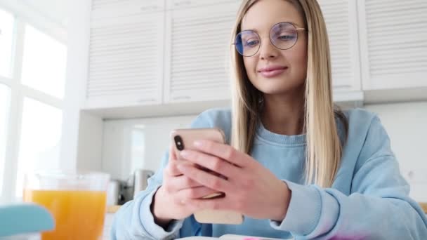 Uma Jovem Loira Bonita Usando Óculos Está Usando Seu Smartphone — Vídeo de Stock