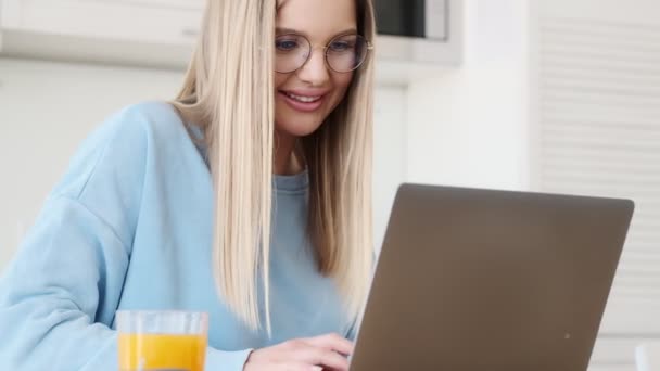 Charming Smiling Young Blonde Woman Wearing Glasses Using Her Laptop — Stock Video
