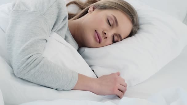 美しい若い女性が家の白いベッドで寝ています — ストック動画