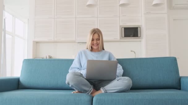 Una Hermosa Joven Rubia Está Usando Computadora Portátil Sentada Sofá — Vídeo de stock