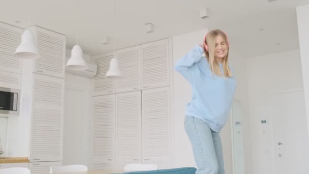 Urocza Blondynka Tańczy Kanapie Słuchając Muzyki Salonie Domu — Wideo stockowe