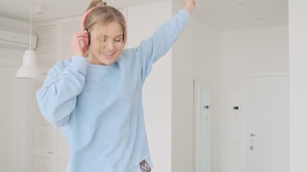 Μια Χαρούμενη Νεαρή Ξανθιά Γυναίκα Απολαμβάνει Ακούει Μουσική Χρησιμοποιώντας Ακουστικά — Αρχείο Βίντεο