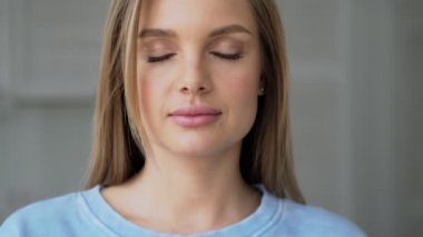 Sarışın, güzel bir kadın gözlerini açıyor ve kameraya bakıyor.